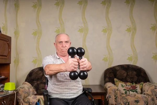 Homme âgé en fauteuil roulant soulevant des haltères à la maison — Photo