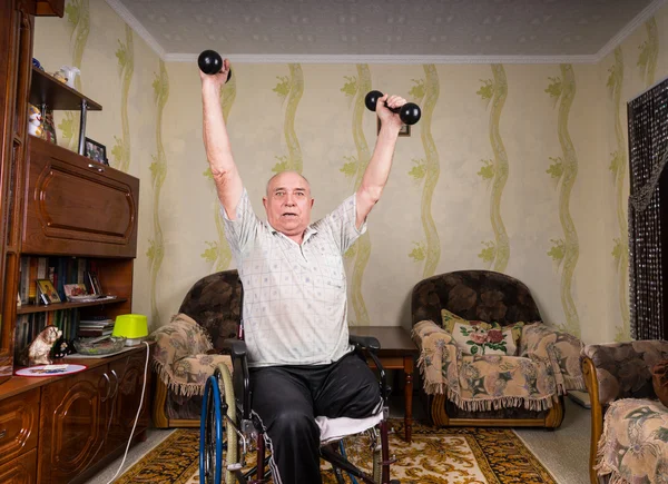 Invalid old man puts his hands up with dumbbells — Stock Photo, Image