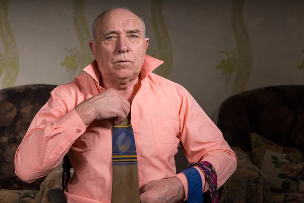 Handsome senior sad man is trying on a tie — Stockfoto