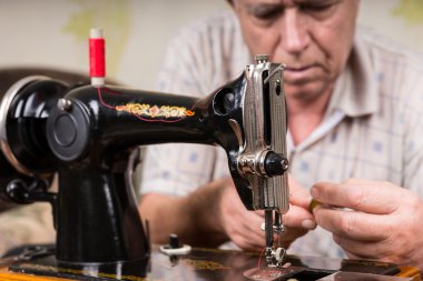 Senior Man Threading Old Fashioned Sewing Machine