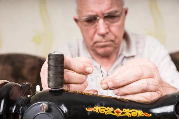 Senior Mann fädelt Nadel der Nähmaschine ein — Stockfoto