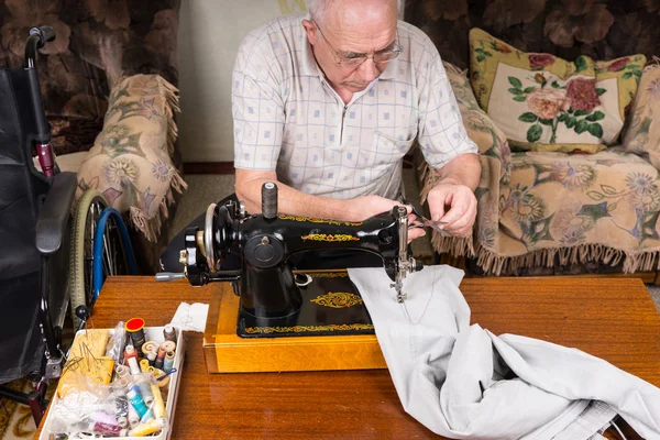 Hombre mayor remendando pantalones con máquina de coser — Foto de Stock