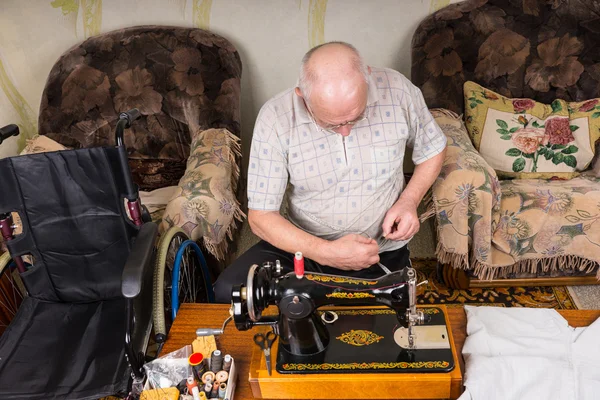 Homem sênior trabalhando na máquina de costura à moda antiga — Fotografia de Stock