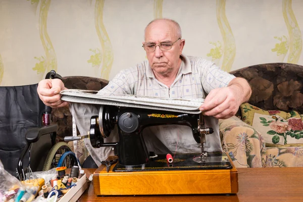 Senior-Mann misst Stoff an Nähmaschine — Stockfoto