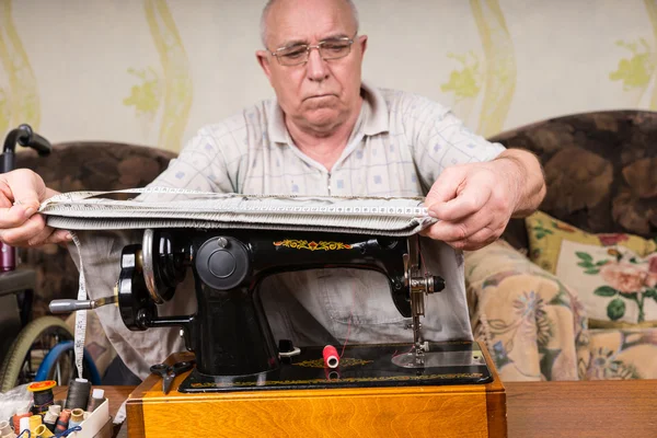 Senior-Mann misst Stoff an Nähmaschine — Stockfoto