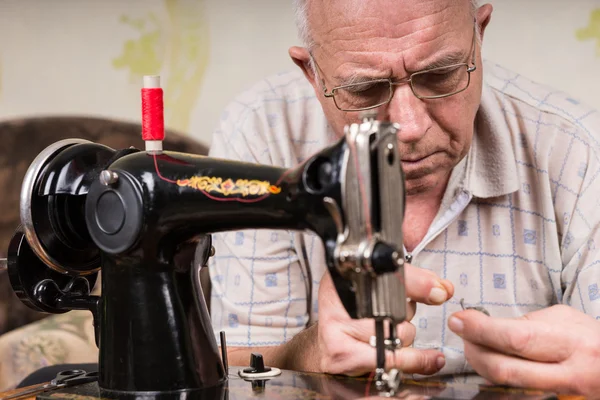 Senior Mann fädelt altmodische Nähmaschine ein — Stockfoto