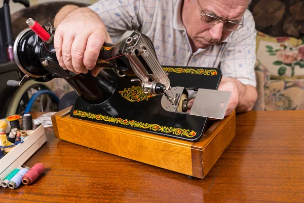 Hombre mayor inspeccionando la máquina de coser de moda antigua — Foto de Stock