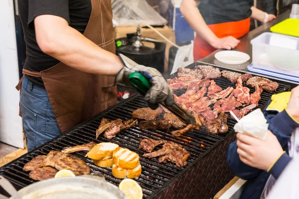 Man med matlagning kött på grillen på Food Festival Stockbild