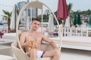 Genç adam bardak bira ile güvertede rahatlatıcı