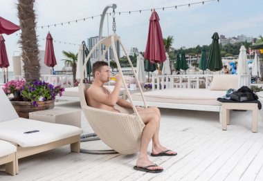Young Man Relaxing on Deck with Glass of Beer clipart