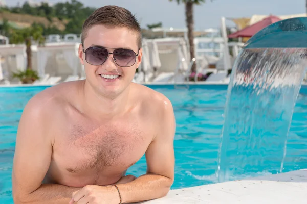 Handsome young man standing in a swimming pool
