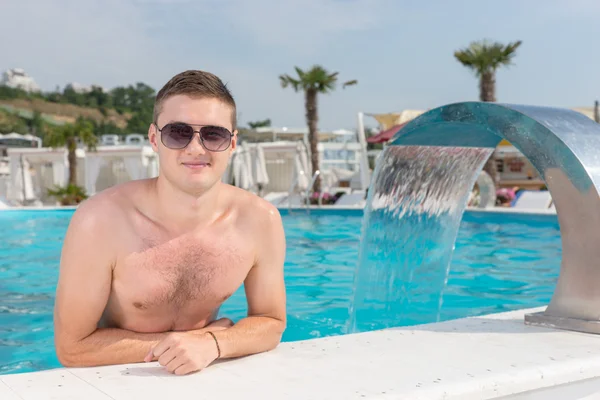 Young man relaxing in a resort swimming pool