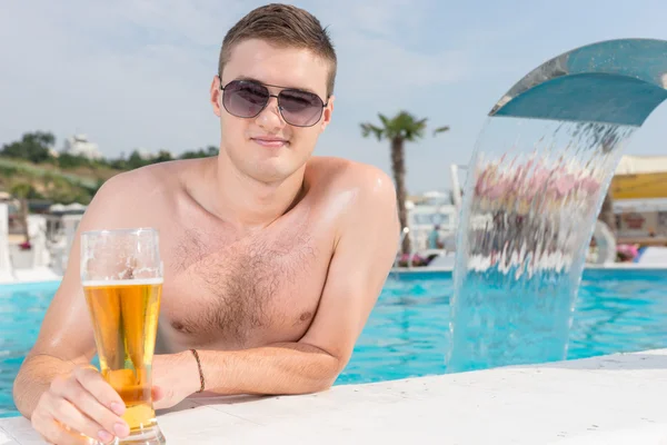 Bel homme dans la piscine avec un verre de bière — Photo