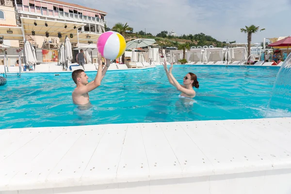 Young couple tossing a beach ball to each other — Stock fotografie