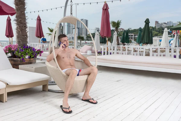 Hombre joven con teléfono celular en la cubierta de lujo Resort — Foto de Stock