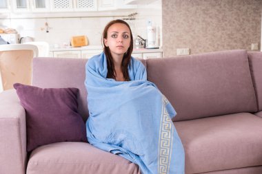 Young Woman on Sofa Wrapped in Blue Blanket clipart