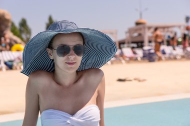 Genç kadın Resort yüzme havuzunun kenarında güneşi şapkalı