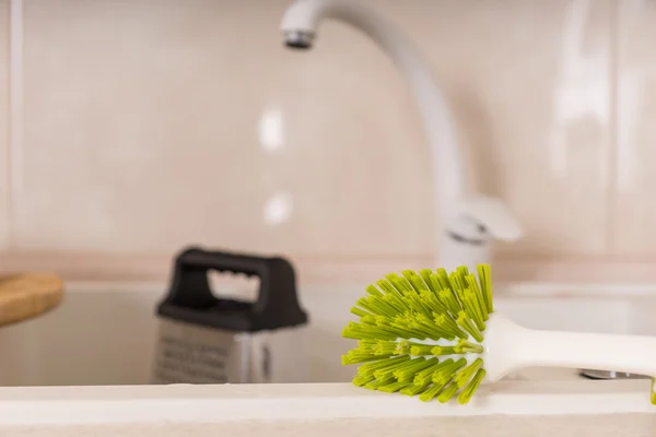 Green Scrub Brush on Edge of Kitchen Sink — Stock Photo, Image