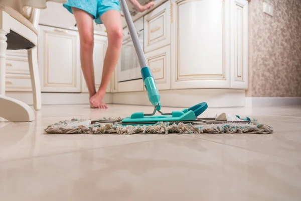 Jeune femme qui nettoie le plancher de cuisine — Photo