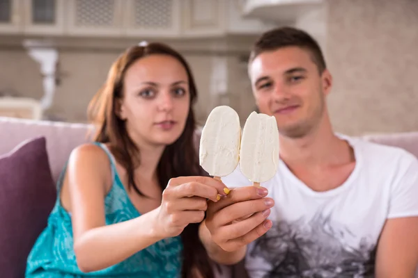 Pareja joven con barras de helado sentada en el sofá — Foto de Stock