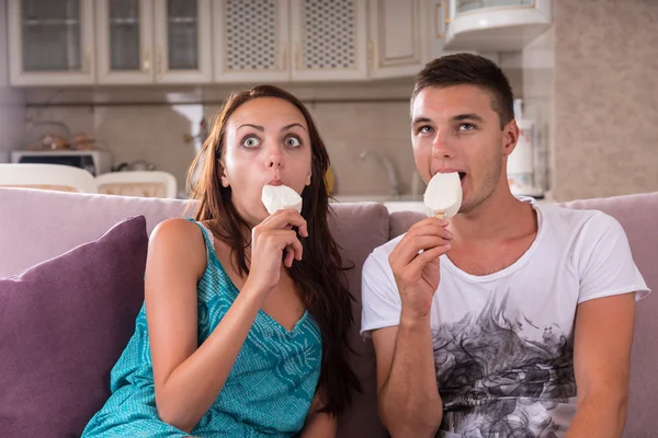 Pareja joven comiendo barras de helado y viendo la televisión —  Fotos de Stock