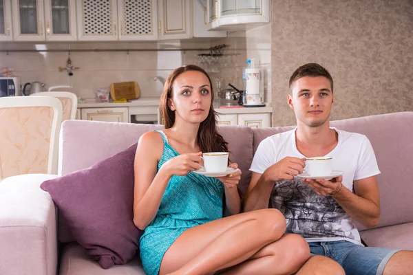 Junges Paar mit Kaffeetassen vor dem Fernseher — Stockfoto