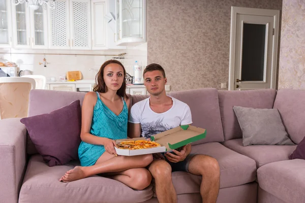 Jovem casal assistindo televisão e comer pizza — Fotografia de Stock