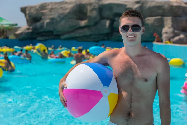 Mladý muž s Beach Ball v bazénu — Stock fotografie