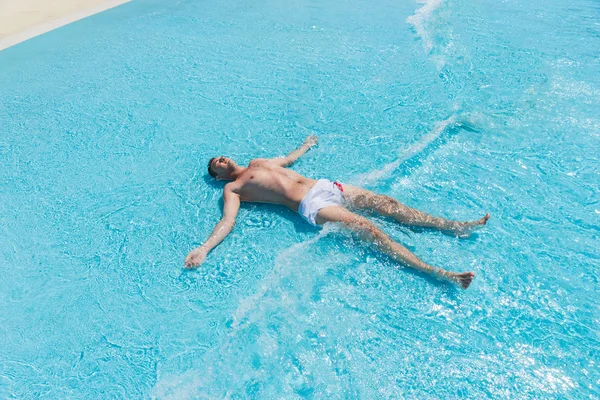 Giovane uomo sdraiato sulla schiena in onde poco profonde di piscina — Foto Stock