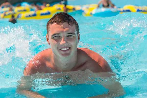 Ung Man som ligger i grunda vågor av simbassäng — Stockfoto