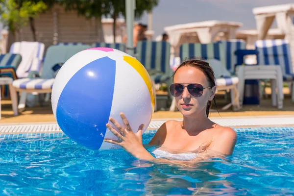 Mulher jovem com bola de praia na piscina — Fotografia de Stock