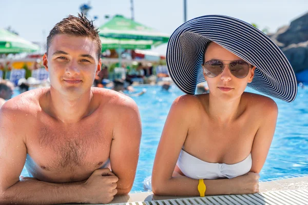 Jeune couple penché sur le bord de la piscine — Photo