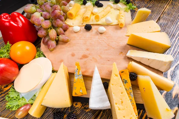 Selection of different cheeses around a board — ストック写真