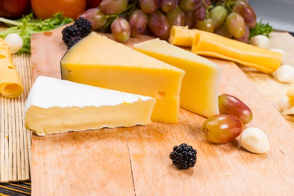 Wedges of assorted cheeses on a board — Stock Photo, Image