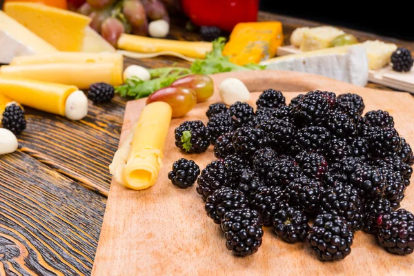 Haufen frischer Brombeeren mit verschiedenen Käsesorten — Stockfoto