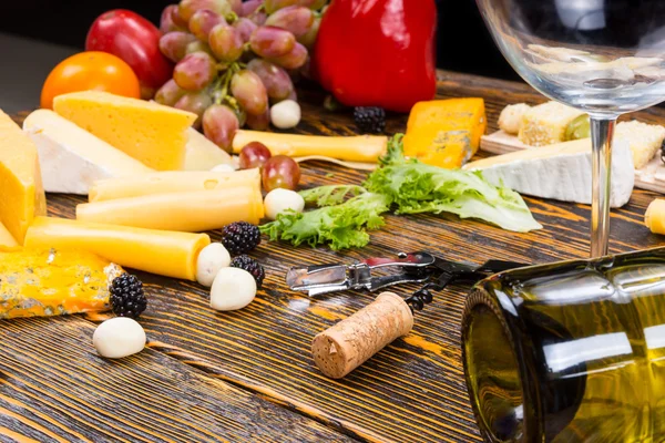 Copa de vino sobre mesa con quesos gourmet y fruta — Foto de Stock