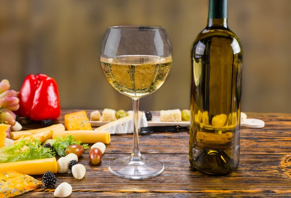 Vino blanco sobre mesa rústica con queso y fruta — Foto de Stock