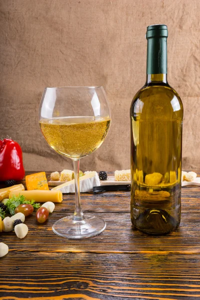 Vino blanco sobre mesa rústica con queso y fruta — Foto de Stock