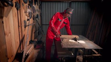 Atölyesindeki bir zanaatkar tahtayı kesmek için dairesel testereyi açar..