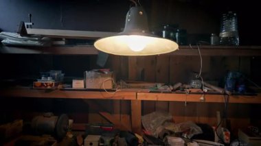 Eski bir ahırda parlak ampullü bir lamba asılıydı..