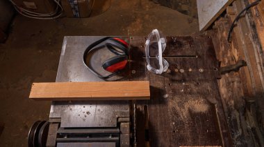 Marangozluk atölyesinde kulak koruyucusu ve koruyucu bir maskeyle birlikte dairesel testere bulunur.