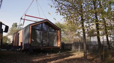 İşçiler, beton yığını üzerine bir modüler evin kurulumunu denetliyor..