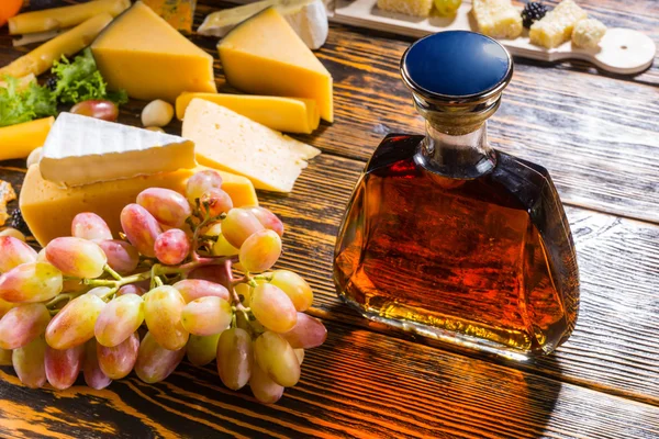 Cheese platter, grapes and a brandy decanter — ストック写真