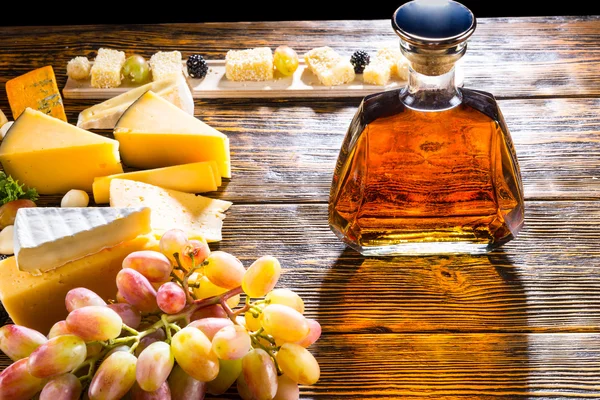 Whiskey or brandy decanter with cheese and grapes — ストック写真