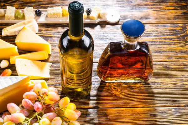 Vino y whisky en la mesa con queso y uvas — Foto de Stock