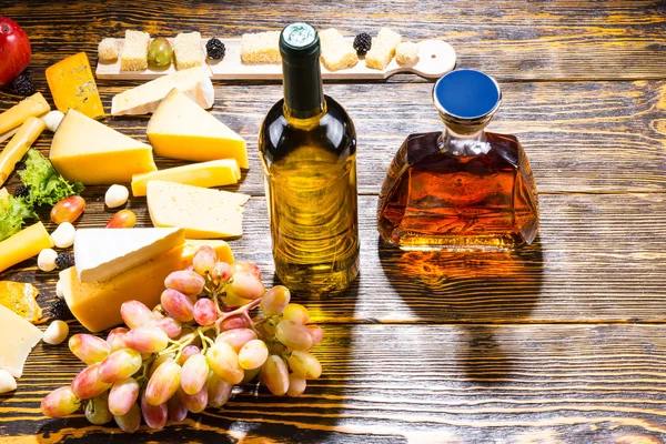 Vino y whisky en la mesa con queso y uvas — Foto de Stock