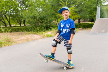 Sevimli emin küçük çocuk bir kaykay üzerinde poz