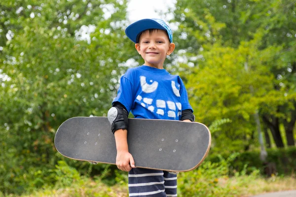 Happy stolt liten pojke bär en skateboard — Stockfoto