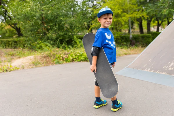 Petit garçon portant son skateboard — Photo