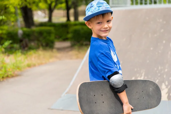 Beau jeune garçon portant un skateboard — Photo